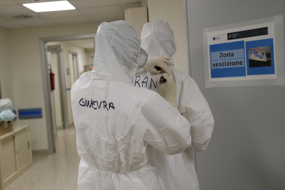 Die Krankenschwestern Ginevra Fattori (l) und Francesca Tulli schreiben ihren Namen auf ihre Schutzanzüge vor ihrer Schicht in der Intensivstation des Krankenhaus San Filippo Neri.