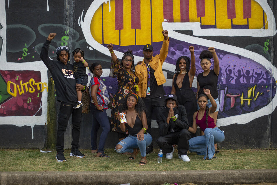 Juneteenth celebrants pose in front of a Black Wall Street mural in Tulsa's historic Greenwood district.