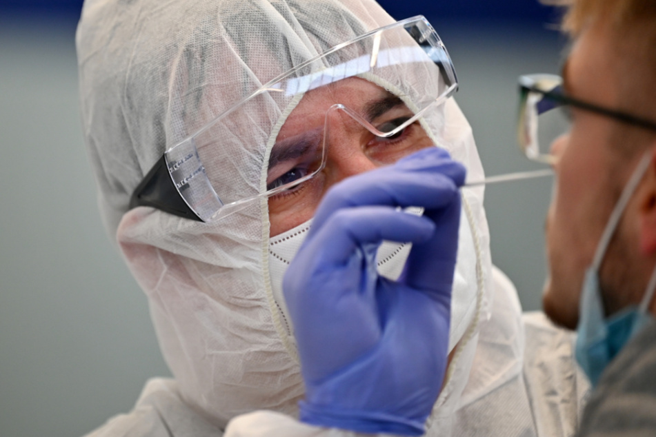 Ein Helfer entnimmt eine Probe für einen Corona-Schnelltest.
