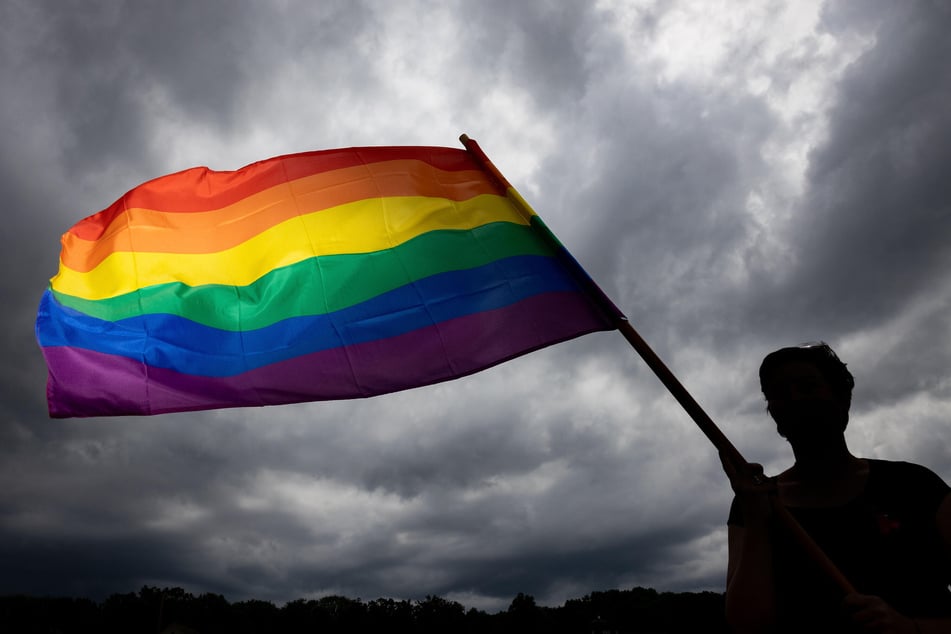 Eine Frau trägt bei der Gedenkfeier für die sogenannten Rosa-Winkel-Häftlinge des Konzentrationslagers Buchenwald im Jahr 2020 die Regenbogenfahne am Gedenkstein. (Archivbild)