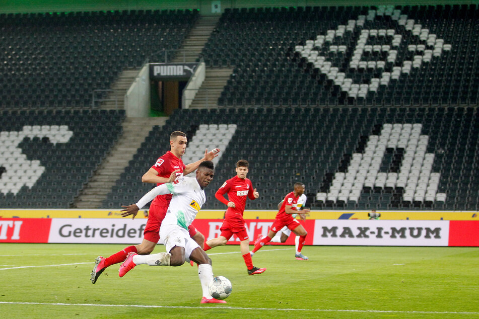 Der Mönchengladbacher Breel Embolo (r) und der Kölner Ellyes Skhiri kämpfen in dem leeren Stadion um den Ball.