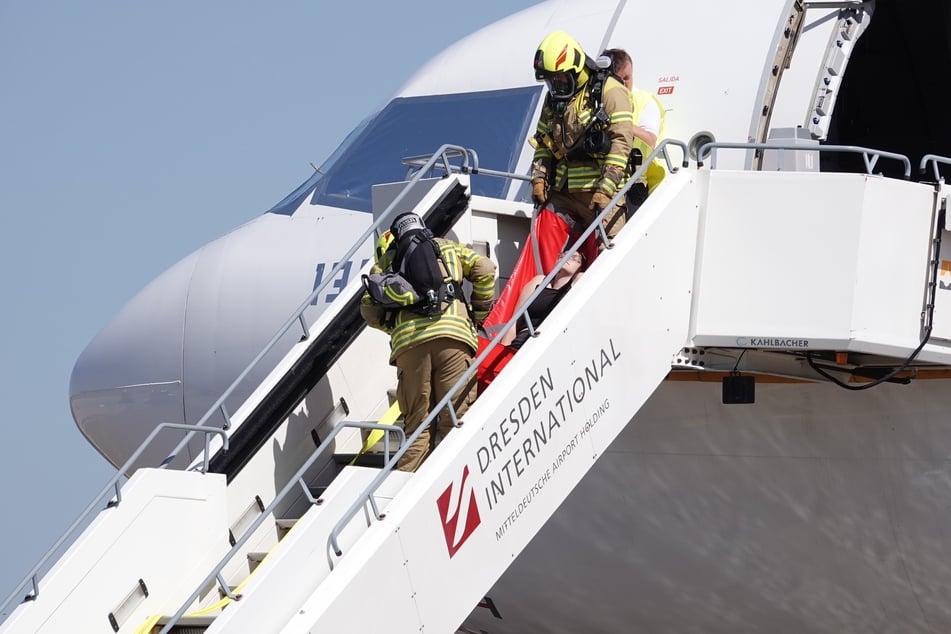 Zwei Feuerwehrleute bringen einen "Verletzten" aus einem Flugzeug.