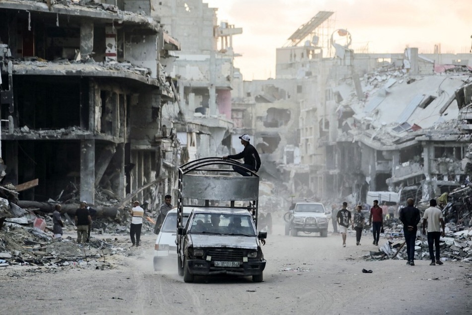 Displaced Palestinians walk and drive along a street devastated by Israeli bombardment in Khan Younis in the southern Gaza Strip.