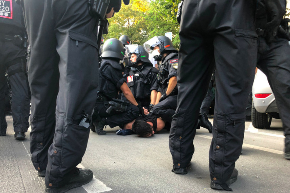 Polizisten nehmen neben der Theresienwiese bei einer Demonstration gegen die Corona-Maßnahmen einen Mann fest.