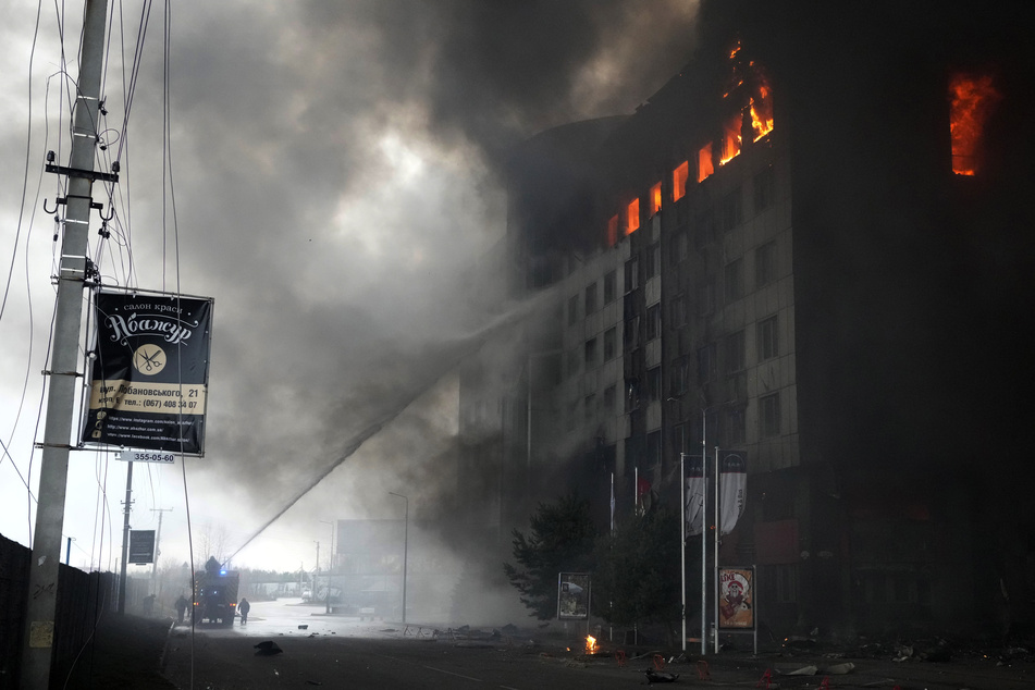 Feuerwehrleute löschen ein brennendes Gebäude nach einer Bombardierung in Kiew.