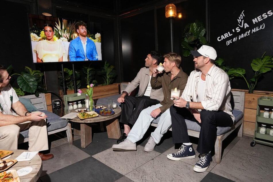 Carl Radke (l.), Kyle Cook and Jesse Solomon look at a screen showing the Summer House reunion featuring Amanda Batula and West Wilson.