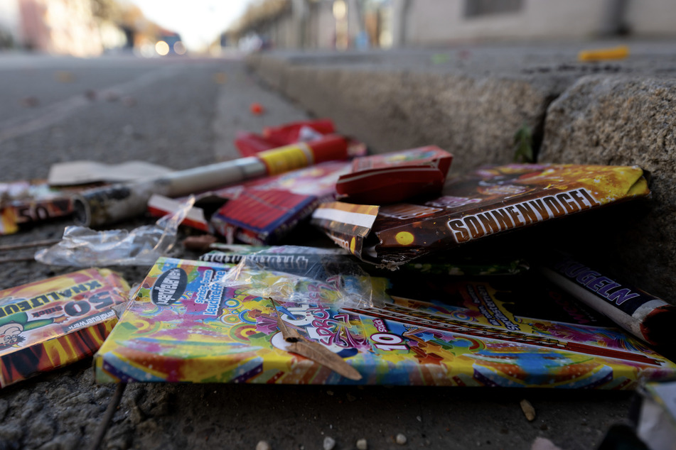 Verpackungen und abgebrannte Feuerwerkskörper liegen auf einer Straße. In München mussten rund 47 Tonnen Müll aus der Silvesternacht beseitigt werden.