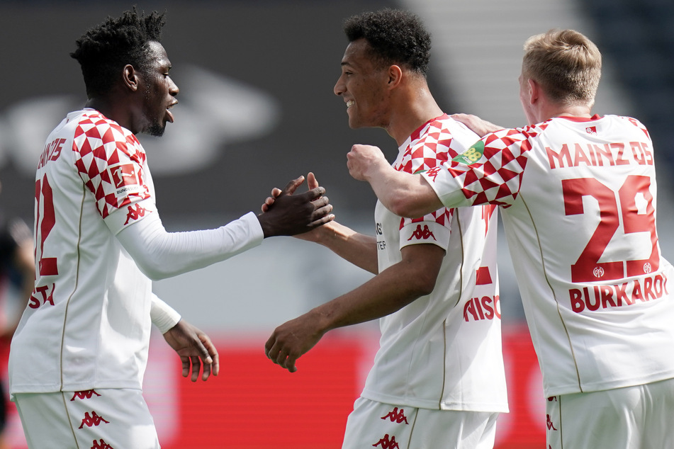 Die Mainzer Danny da Costa (l.) und Jonathan Burkardt (r.) bejubeln den Treffer von Karim Onisiwo zum 1:0 gegen Eintracht Frankfurt.