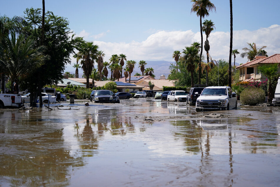 Cars partially submerged in water and mud sit on a street following Tropical Storm Hilary in Cathedral City, California.