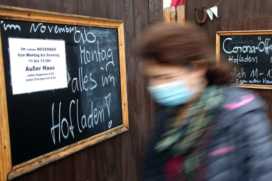 Eine Frau geht an einem Restaurant vorbei, das nur noch Speisen außer Haus verkauft.
