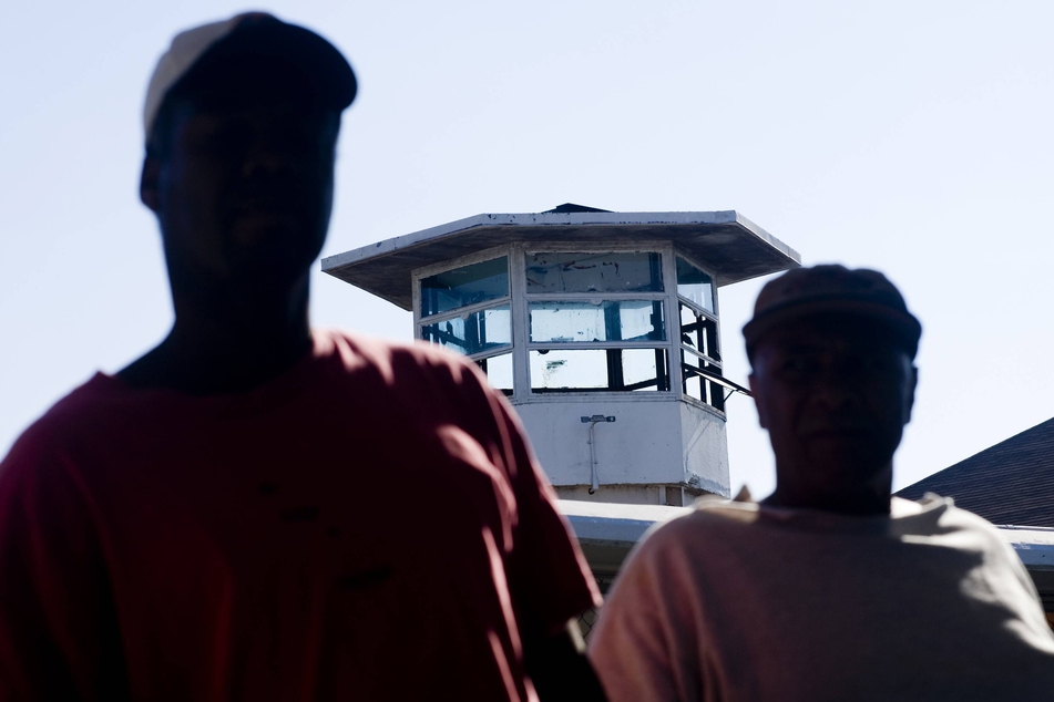 Incarcerated people stand in front of a guard tower at the infamous Louisiana State Penitentiary, known as Angola.