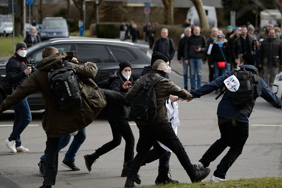 Anhänger der Querdenker-Bewegung versuchen einem Gegendemonstranten ein Banner zu entreißen. Ein Fotograf, der die Szene dokumentierte, soll daraufhin einen Faustschlag ins Gesicht erhalten haben.