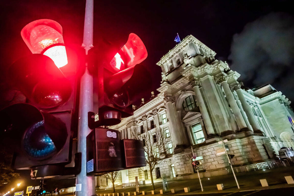 Eine rote Ampel leuchtet vor dem Reichstagsgebäude bei Nacht. In Berlin zeigen zwei Corona-Warnampeln weiterhin rot. (Symbolfoto)