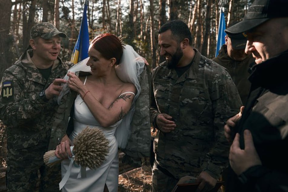 Ein Kamerad legt der Braut eine Soldatenjacke um.