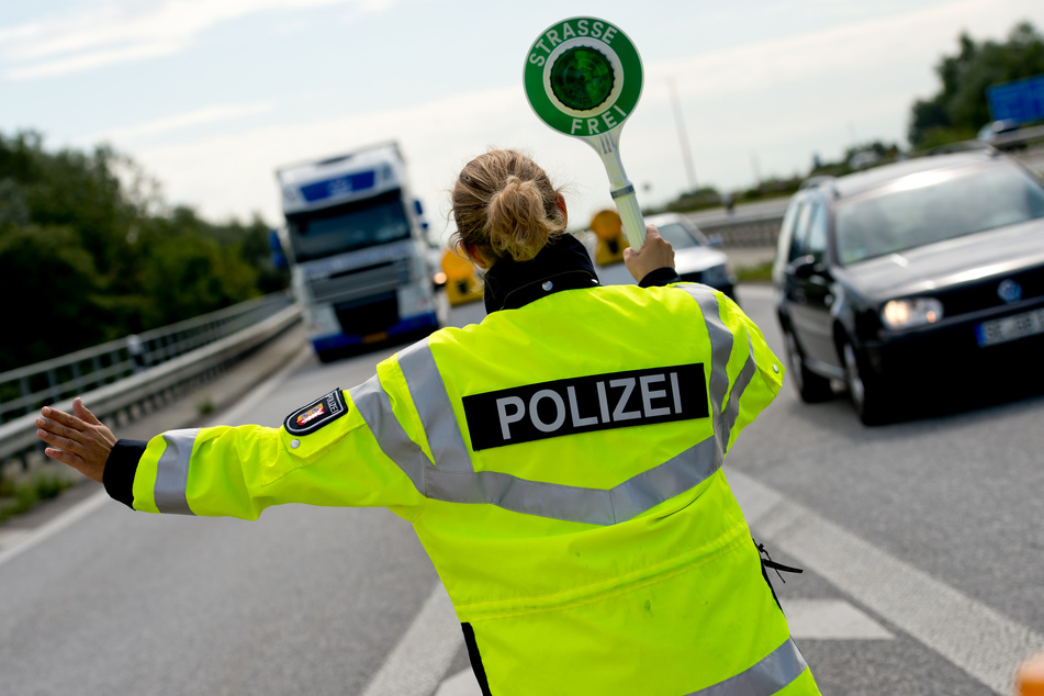 Eine Polizeibeamtin winkt auf der A7 einen Lastwagen von der Autobahn.