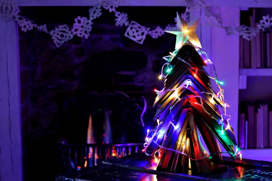Eine von zahlreichen Alternativen zum Weihnachtsbaum ist ein Christbaum aus Büchern mit bunter Lichterkette und Papierstern.