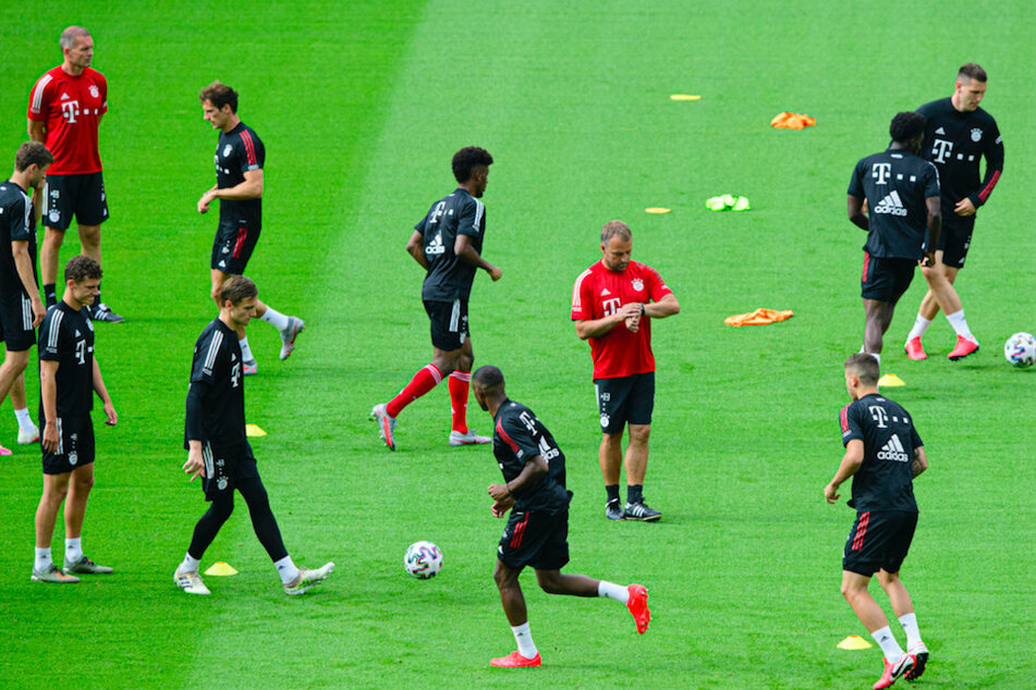 Bayern Münchens Trainer Hansi Flick (M) schaut beim Training im Olympiastadion inmitten seiner Spieler auf die Uhr.