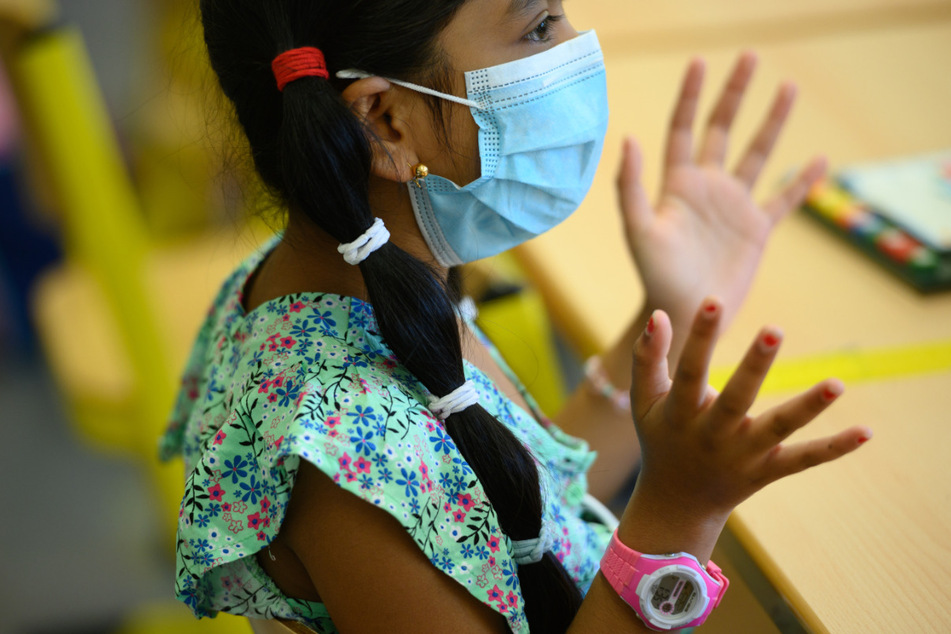 Bushra (7) aus Frankfurt/Main sitzt im Klassenzimmer und trägt eine Maske.
