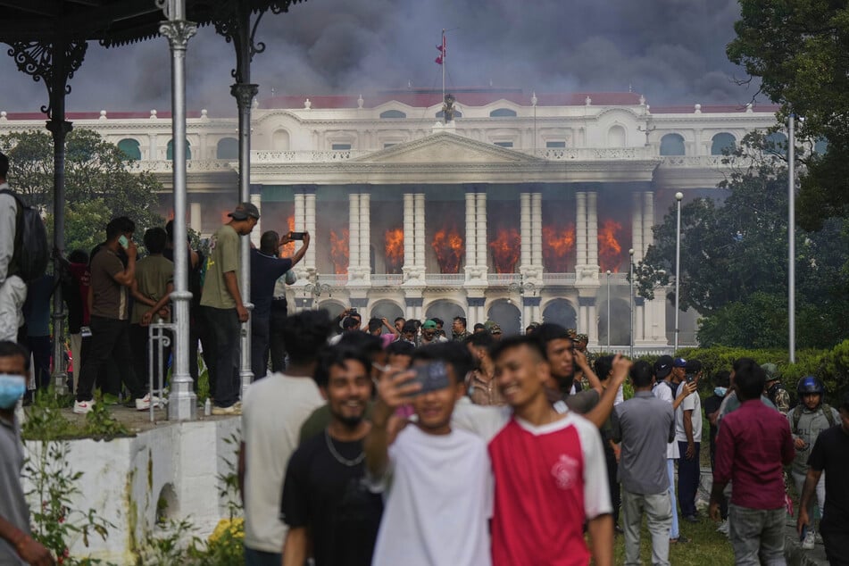 Los jóvenes celebran frente al edificio del parlamento en llamas su “éxito” tras la caída del gobierno.