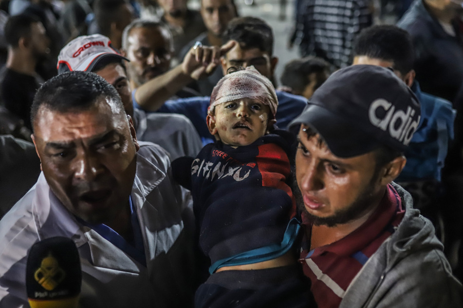 Palästinenser tragen ein Kind aus dem Ahli Arab Krankenhaus in Richtung Al-Shifa Krankenhaus im Gazastreifen.