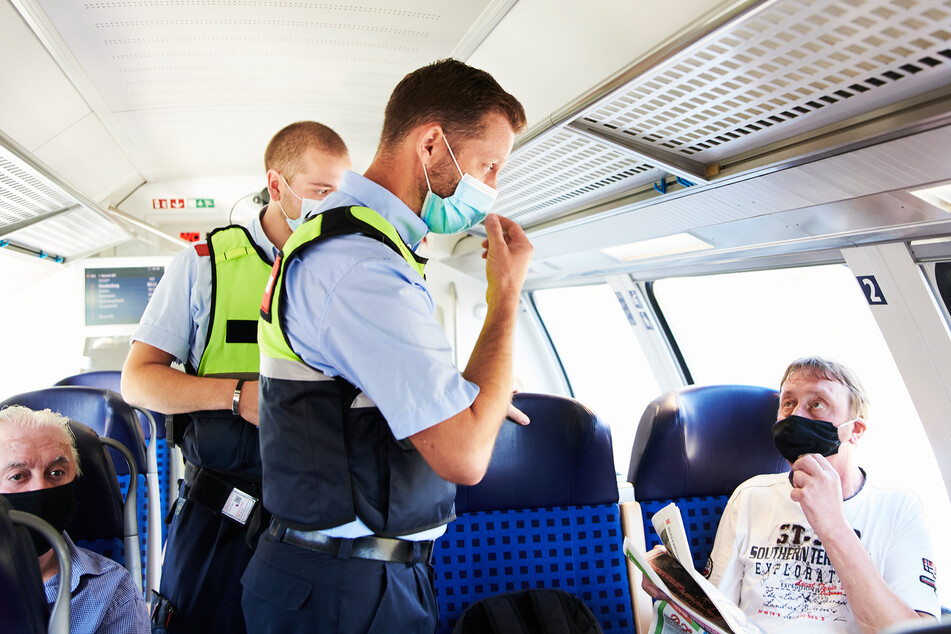 Mitarbeiter der DB Sicherheit und Beamte der Bundespolizei gehen durch einen Zug und kontrollieren, ob alle Reisenden ihre Masken korrekt tragen.