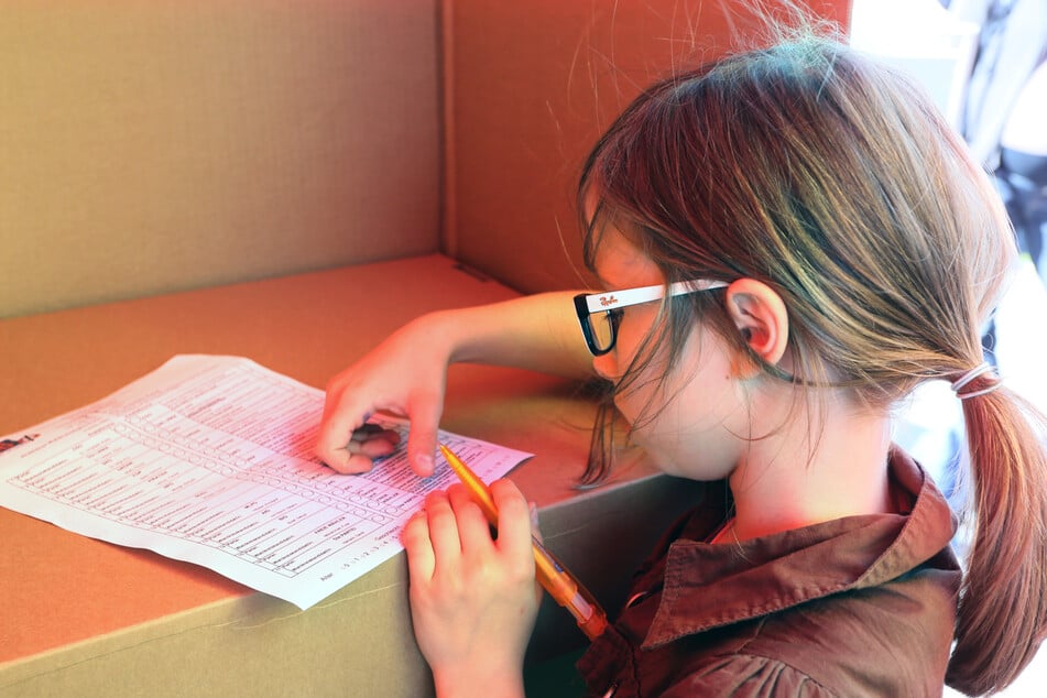 Lilly (8) bei der U18-Wahl in der Wahlkabine. Bei diesen fiktiven Wahlen werden die politischen Präferenzen junger Menschen in Deutschland ermittelt. (Archivbild)