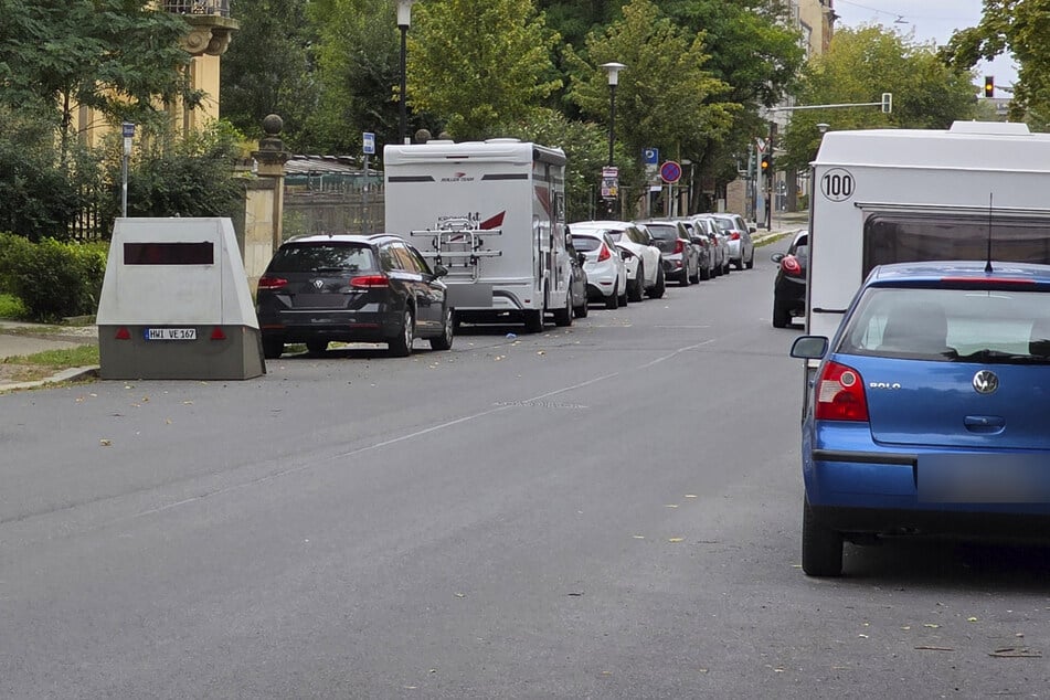 Zwischen den parkenden Autos versteckt, steht der Enforcement Trailer und überwacht die Geschwindigkeit der vorbeifahrenden Autofahrer.