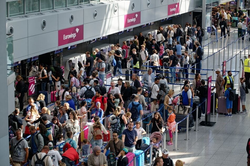 Zahlreiche Reisende warten an Schaltern im Flughafen Düsseldorf auf die Abfertigung.