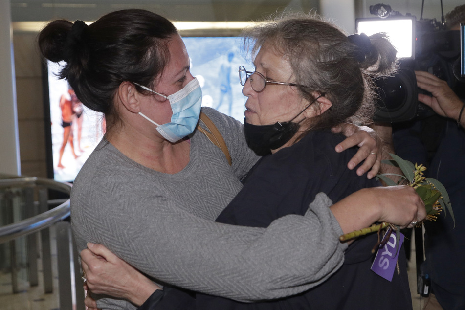 Eine Frau (r) wird von einem geliebten Menschen umarmt, nachdem sie mit einem Flug aus Los Angeles auf dem Flughafen von Sydney angekommen ist, als Australien am Montag zum ersten Mal seit 20 Monaten seine Grenzen öffnete.