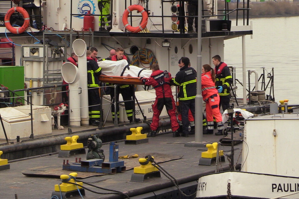 Einsatzkräfte tragen einen Leichnam von Bord.