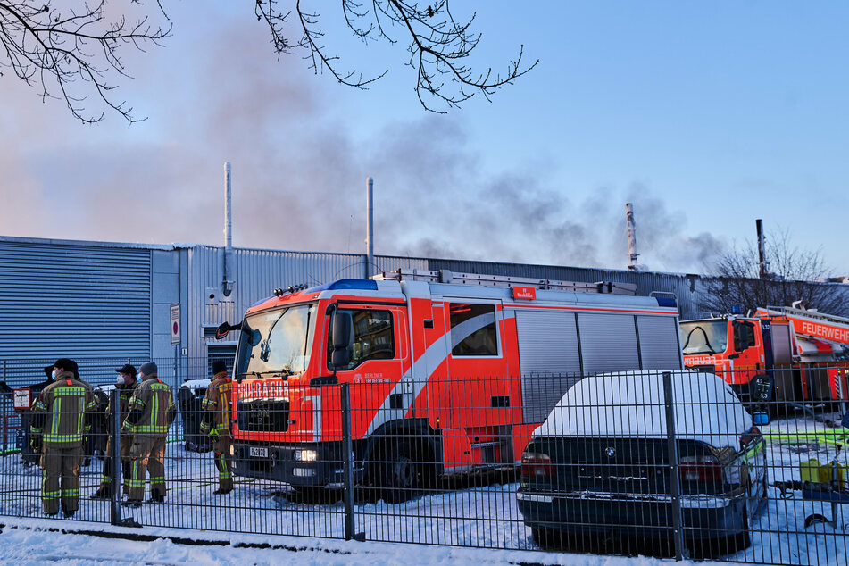 Feuerwehrmänner und Wägen stehen vor der Halle in Marienfelde.
