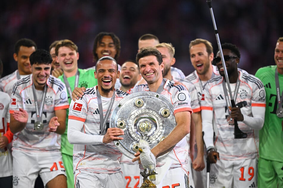Münchens Leroy Sane (29, l.) und Thomas Müller (35) jubeln mit der Meisterschale. Davor steht die mysteriöse Kakadu-Figur.