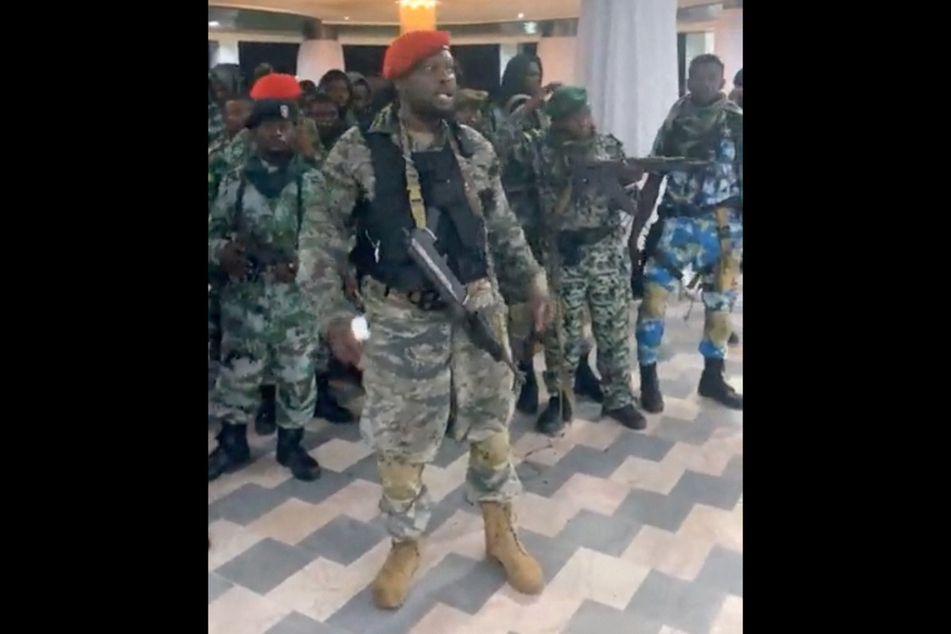 A man in military fatigues speaks as others stand next to him inside the Palace of the Nation during an attempted coup in Kinshasa, Democratic Republic of the Congo.