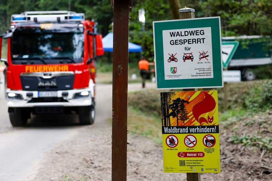 Schilder, die auf die Waldbrandgefahr und die Sperrung für Autos und Motorräder hinweisen, stehen an einem Waldweg in Roetgen.
