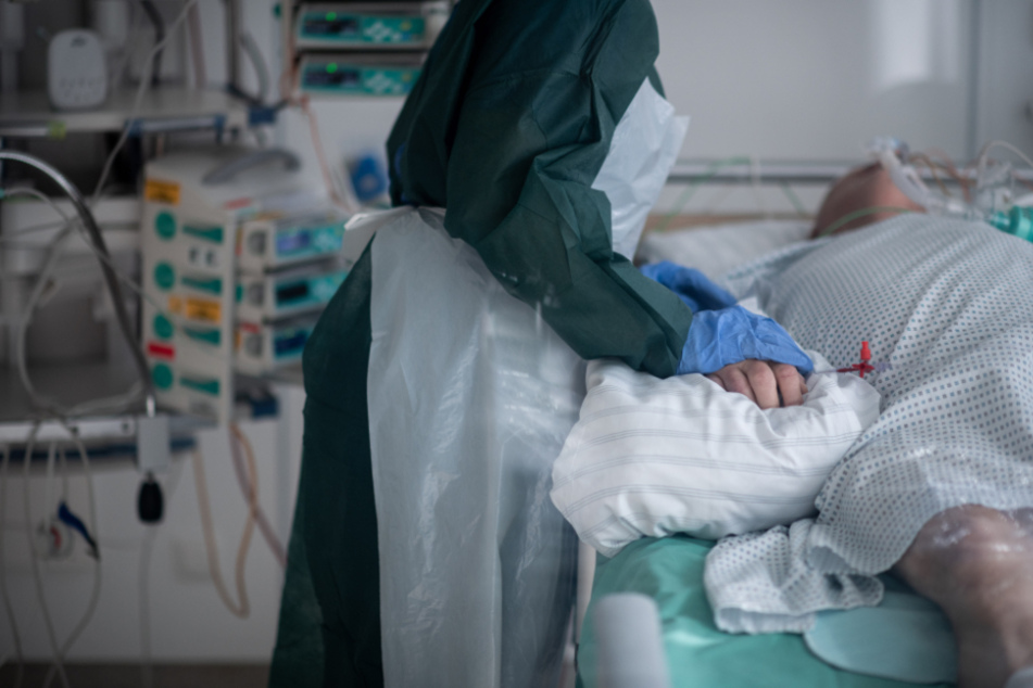 Eine Mitarbeiterin in Schutzausrüstung betreut einen Corona-Patienten. (Symbolbild)