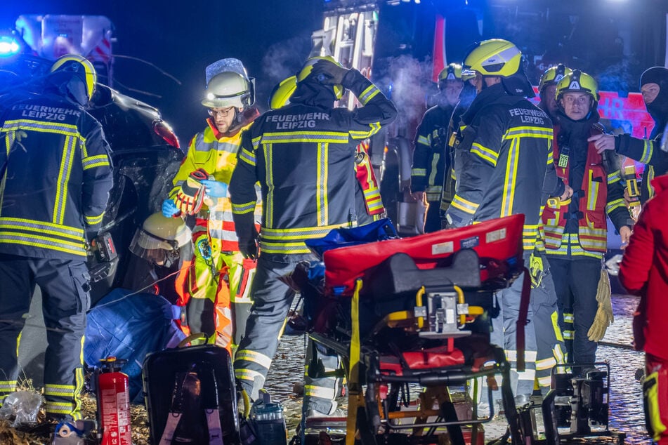 Kräfte von Feuerwehr und Rettungsdienst bei der Rettung des 21-Jährigen. Der junge Mann war in der Nacht zu Sonntag in Leipzig mit seinem Mercedes mit einem Betonmast kollidiert.