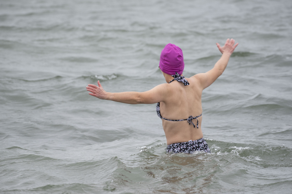 Eine Frau beim Baden am Ostseestrand in Rostock-Warnemünde. Trotz der aktuell milden Temperaturen überlegt der ein oder andere wohl dennoch, wirklich ins kalte Nass zu steigen.