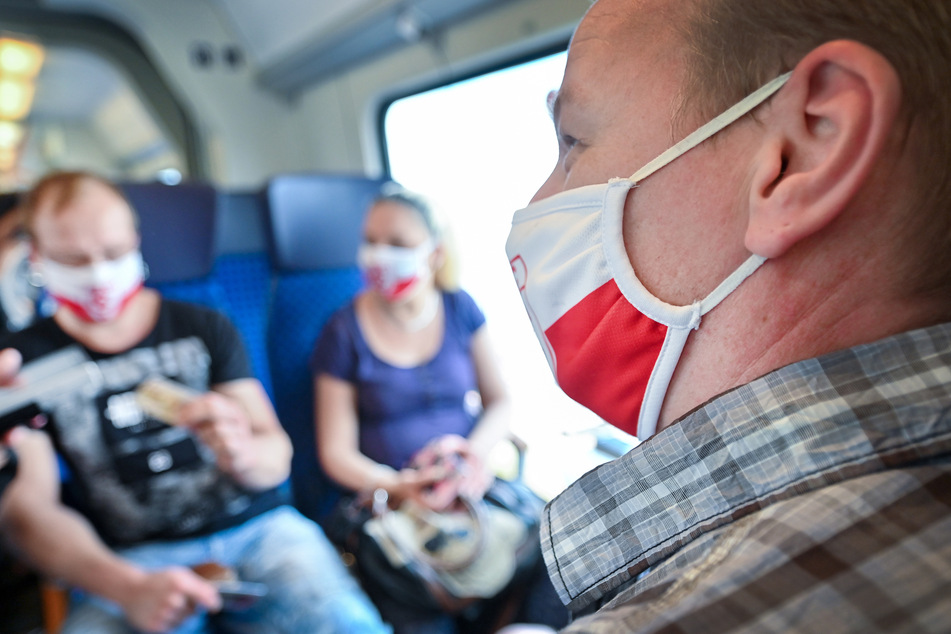 Reisende mit Masken in einem Zug der Deutschen Bahn in Halle. Sieben der 17 neuen Fälle in der Stadt sollen laut OB Wiegand auf Busreisen, Urlaub oder Besucher aus dem Ausland zurückzuführen sein.