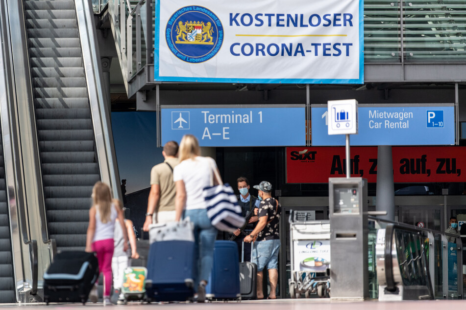 Reisende gehen am Flughafen in Richtung eines Banners mit der Aufschrift "Kostenloser Corona-Test". Für alle Fluggäste werden am Flughafen kostenlose Corona-Tests angeboten.