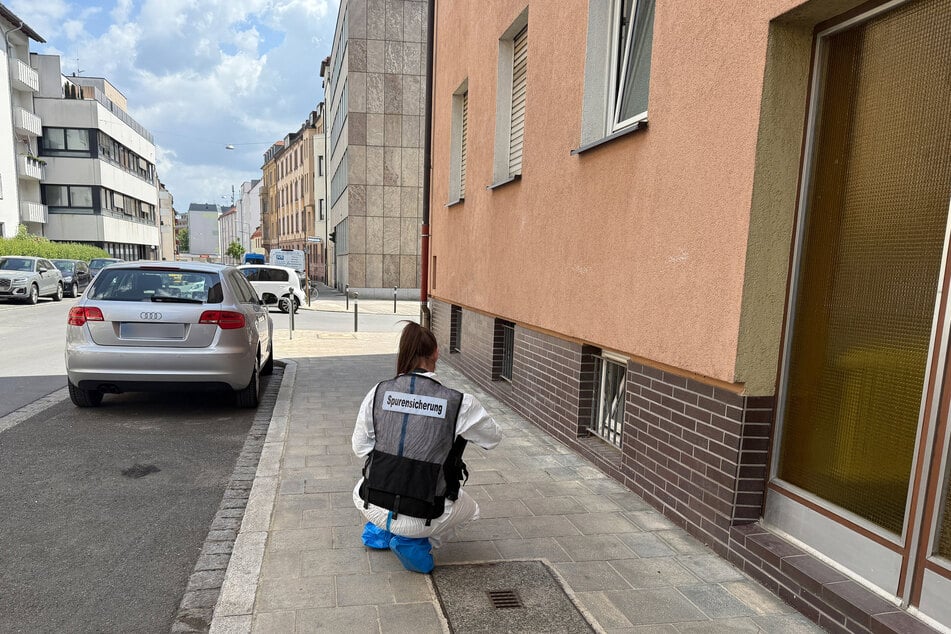 Eine Mitarbeiterin der Spurensicherung sitzt vor dem Haus in der Feldgasse.