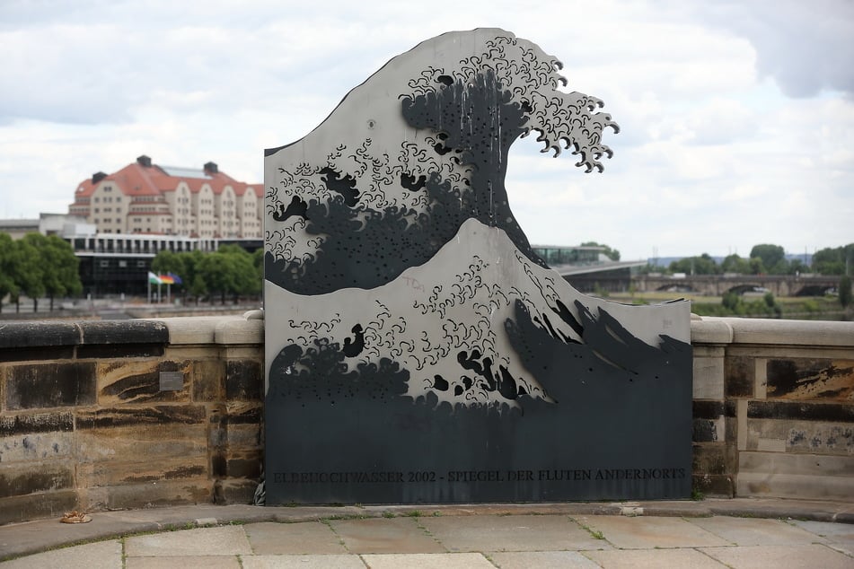 Die Skulptur "Die Woge" (2006) von Tobias Stengel soll an die Flut von 2002 erinnern und ist zwischen den Tafeln "Das Wasser kommt. Was passiert?" und "Leben am Fluss" auf der Augustusbrücke zu finden.