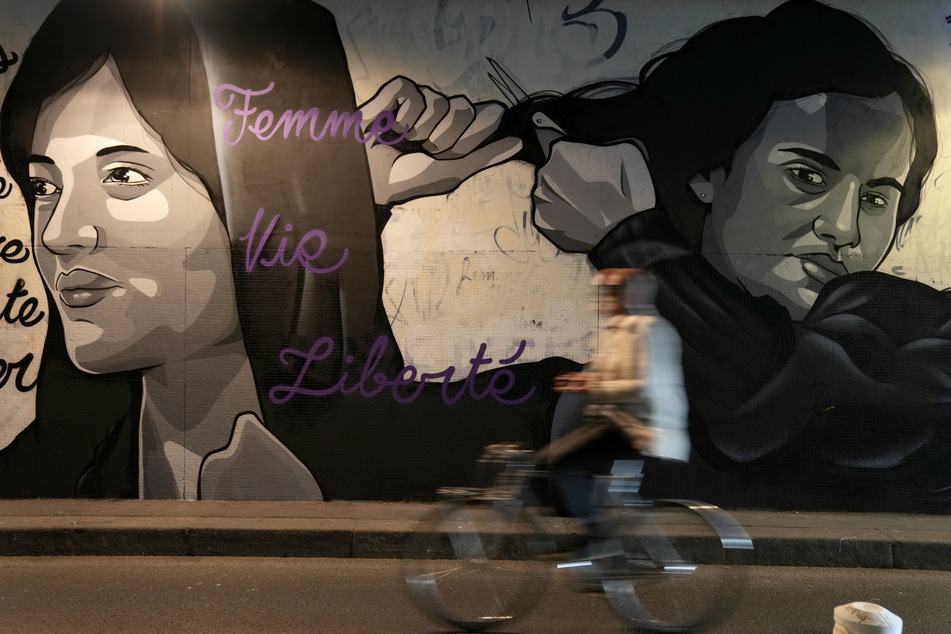 Ein Wandgemälde in Paris illustriert den Protest gegen das brutale Vorgehen iranischer Sicherheitskräfte gegen regierungskritischer Demonstranten. Zahlreiche weibliche Promis schnitten sich aus Solidarität die Haare ab.