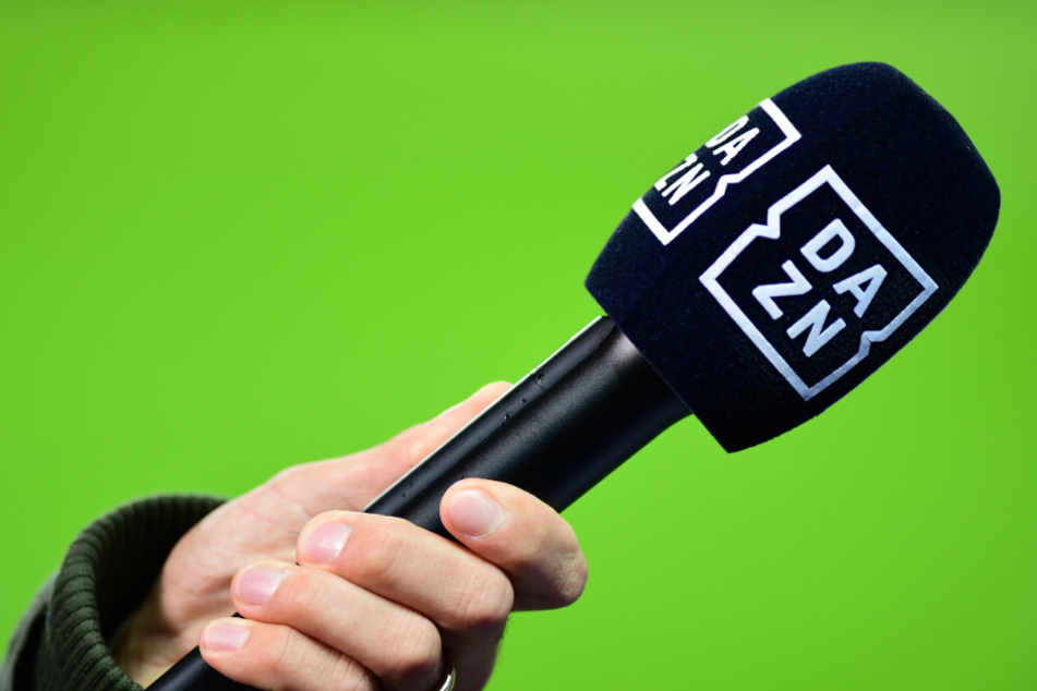 Ein Reporter hält das Mikrofon mit der Aufschrift DAZN in die Kamera.