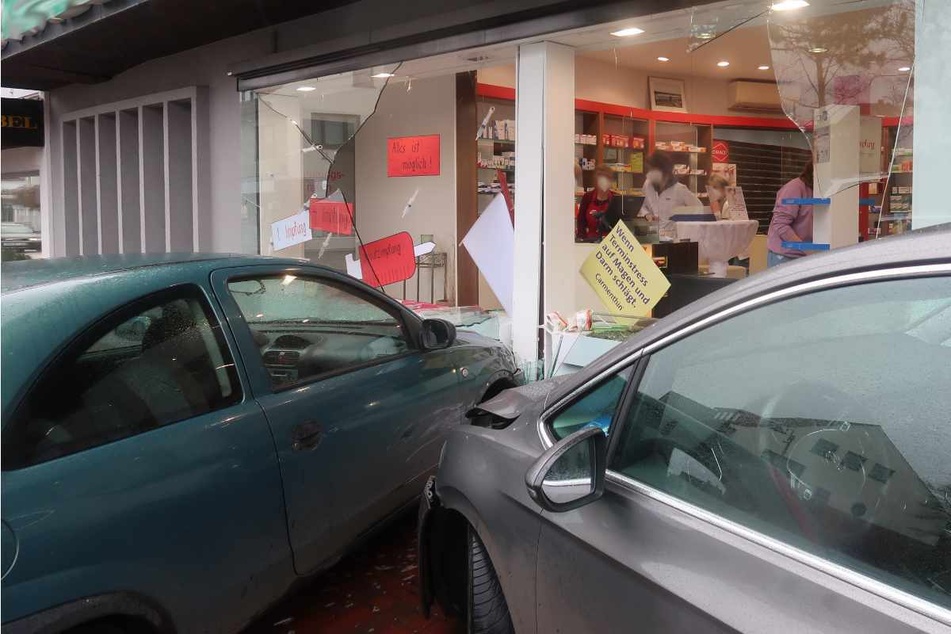Autos krachen nach Unfall gegen Fensterscheibe von Apotheke