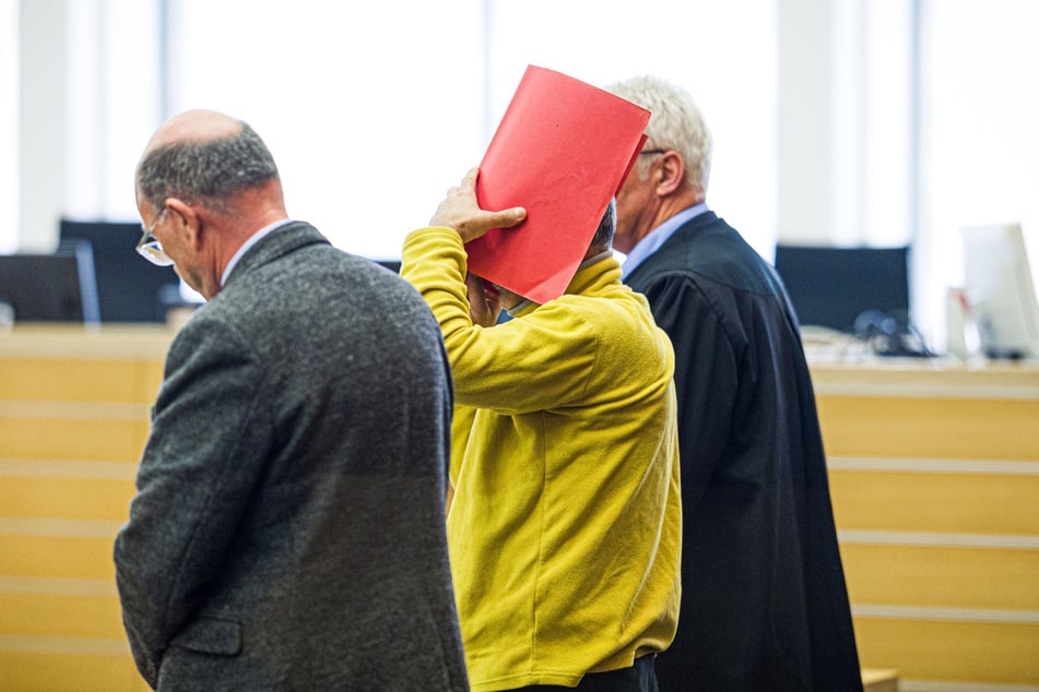 Der 40-jährige Angeklagte (Mitte) soll seine schlafende Frau Brandbeschleuniger übergossen und angezündet haben.