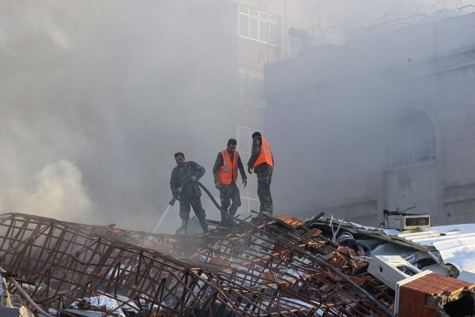 Emergency personnel extinguish a fire at the site of strikes which hit a building next to the Iranian embassy in Syria's capital Damascus.