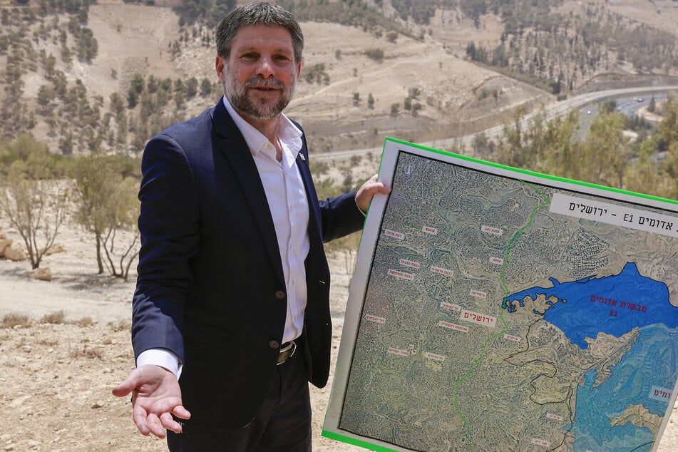 Israeli far-right Finance Minister Bezalel Smotrich holds a map of an area near the settlement of Maale Adumim, a land corridor known as E1, outside Jerusalem in the occupied West Bank, on August 14, 2025.