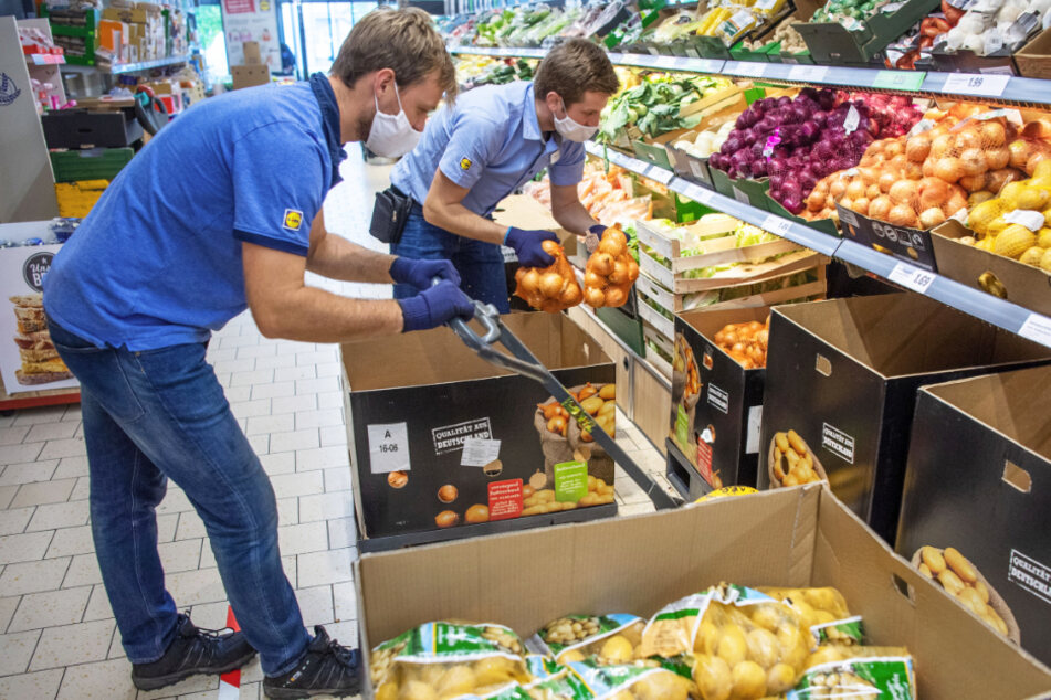 Arbeit in Zeiten der Corona-Krise: Kevin Krawietz (l.) räumt in einem Discounter Kartoffeln neben dem Filialleiter Mirnis Terzic (r.) in ein Regal ein.