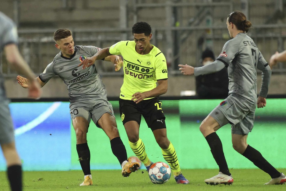 Finn Ole Becker (links) und Jackson Irvine (rechts) versuchen Jude Bellingham zu stoppen.