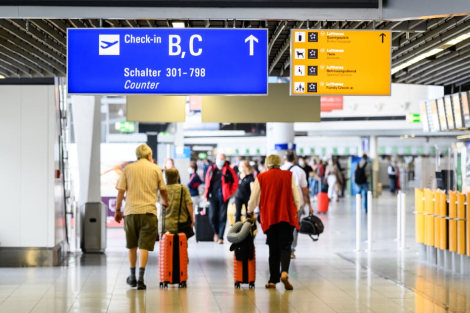 Reisende gehen am Flughafen mit Gepäck durch die Abflughalle im Terminal 1.